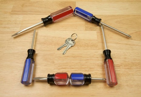 House shaped by screwdrivers and keys on a wood background