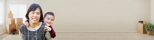 Banner of chinese mother and mixed-race child inside empty room with moving boxes and plants
