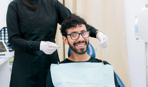 Dentist examining mouth to smiling patient