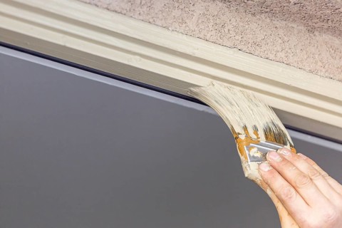 Professional painter cutting in with A brush to paint house door frame
