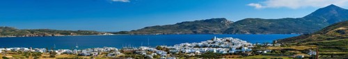 View of Plaka village with traditional Greek church and white painted houses and ocean coast. Milos island