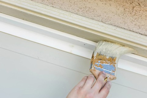 Professional painter cutting in with A brush to paint garage door frame