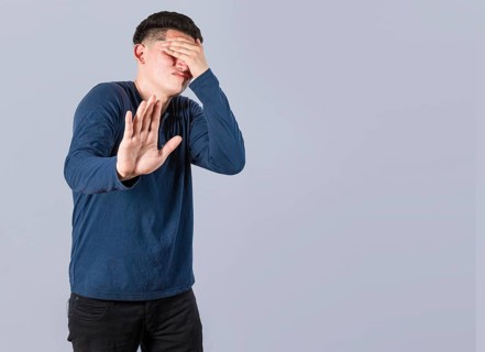 Scared confused man closing eyes with palm of hand