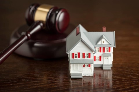 Gavel and small model house on wooden table