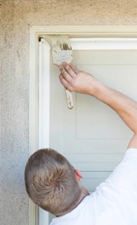 Professional painter cutting in with A brush to paint garage door frame
