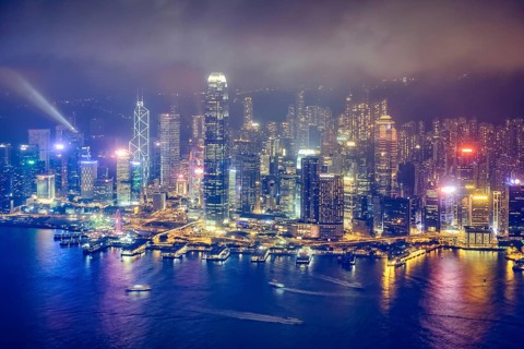 Aerial view of illuminated Hong Kong skyline cityscape downtown skyscrapers over Victoria Harbour in the evening. Hong Kong