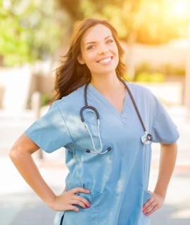 Portrait of young adult female doctor or nurse wearing scrubs and stethoscope outside