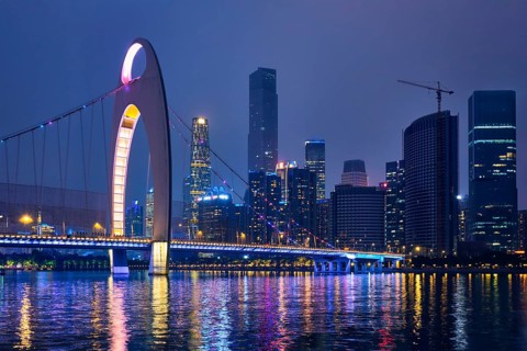 Guangzhou cityscape skyline over the Pearl River with Liede Bridge illuminated in the evening. Guangzhou