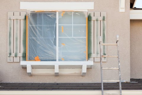 Construction ladder leaning up against A house being painted