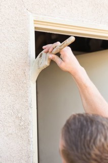 Professional painter cutting in with A brush to paint house door frame