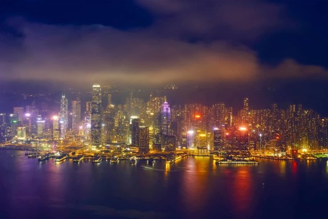 Aerial view of illuminated Hong Kong skyline cityscape downtown skyscrapers over Victoria Harbour in the evening. Hong Kong