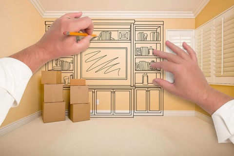 Hands drawing beautiful entertainment unit in room with moving boxes