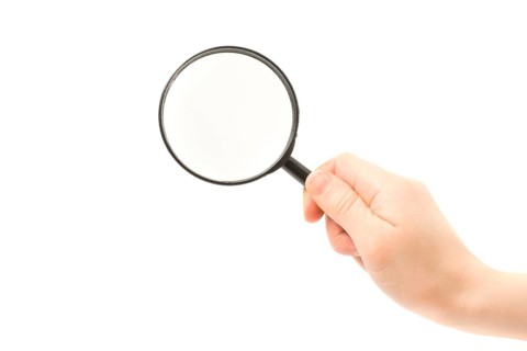Woman hand holding magnifying glass isolated on white background