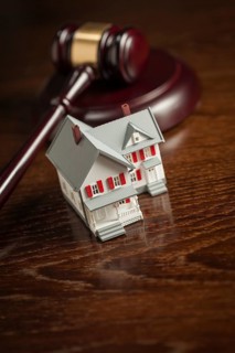Gavel and small model house on wooden table