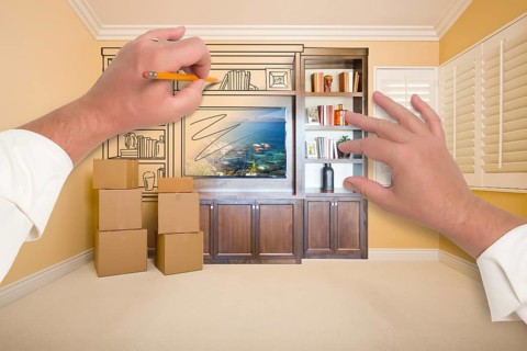 Hands drawing beautiful entertainment unit in room with moving boxes