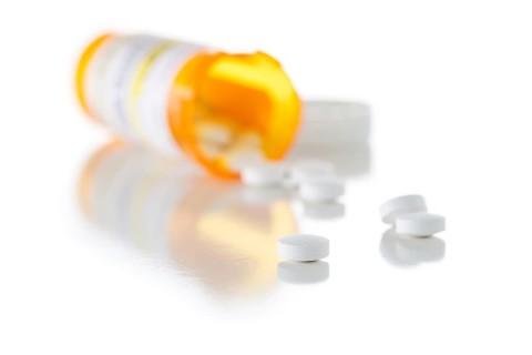 Non-Proprietary medicine prescription bottle and spilled pills isolated on a white background