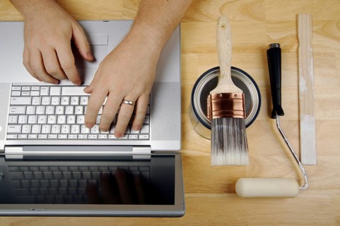 Handyman researches on laptop with paint brush