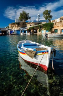Fishing boats moored in crystal clear turquoise sea water in harbour in Greek fishing village of Mandrakia