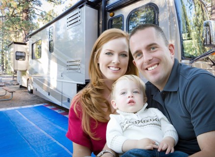 Happy young military family in front of their beautiful RV at the campground