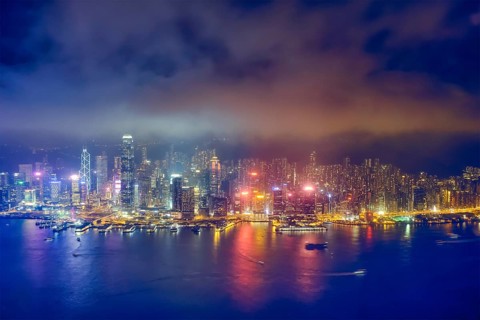 Aerial view of illuminated Hong Kong skyline cityscape downtown skyscrapers over Victoria Harbour in the evening. Hong Kong