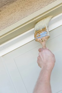 Professional painter cutting in with A brush to paint garage door frame