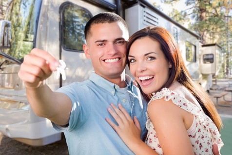 Young military couple holding keys in front of new RV