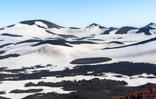 Barren hilly volcanic landscape of snow and lava fields