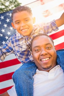 African american father and mixed-race son piggy back with american flag