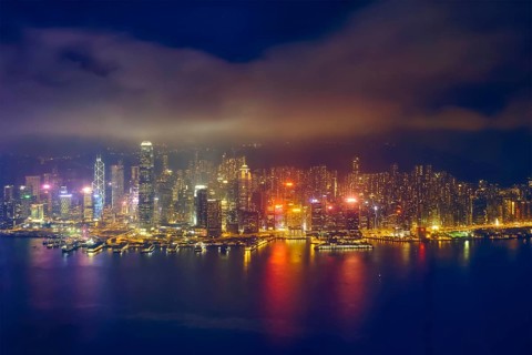 Aerial view of illuminated Hong Kong skyline cityscape downtown skyscrapers over Victoria Harbour in the evening. Hong Kong