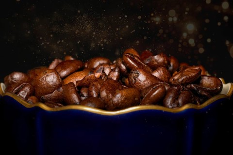 Roasted coffee of the Arabica variety in a porcelain cup in cobalt blue with gold rim