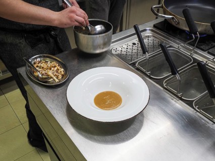 Chef plating pan cooked flambe atlantic squid with potato rich sauce cream reduction
