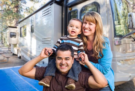 Happy young mixed-race family in front of their beautiful RV at the campground