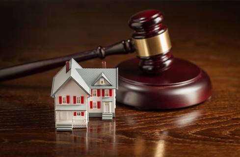 Gavel and small model house on wooden table