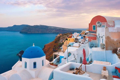 Famous view from viewpoint of Santorini Oia village with blue dome of whitewashed greek orthodox Christian church of traditional greek architecture. Oia town