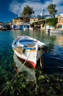 Fishing boars moored in crystal clear turquoise sea water in harbour in Greek fishing village of Mandrakia