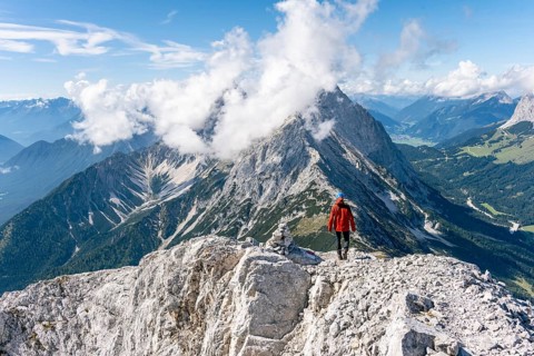 Hiker with climbing helmet on a steep rocky ridge