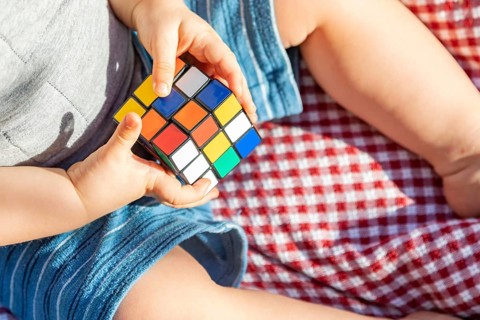 Baby boy sitting on picnic blanket playing with Rubki's Cube