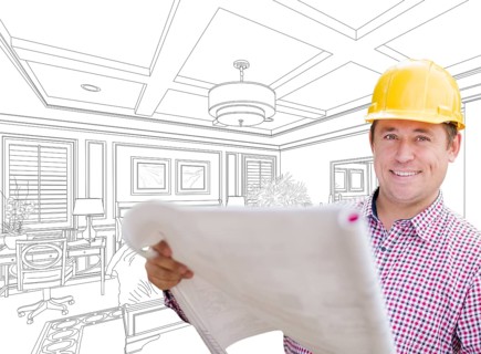 Smiling contractor in hard hat with level over custom bedroom drawing