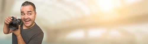Goofy hispanic man with DSLR camera wide banner with room for copy