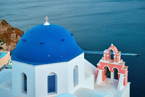 Famous view from viewpoint of Santorini Oia village with blue dome of whitewashed greek orthodox Christian church of traditional greek architecture