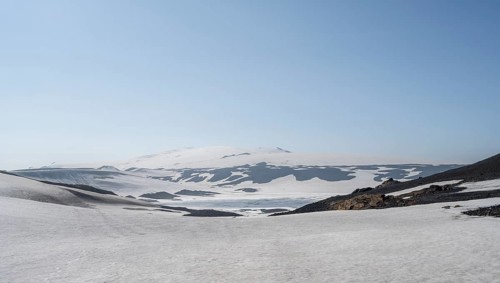 Barren volcanic landscape of snow and lava sand
