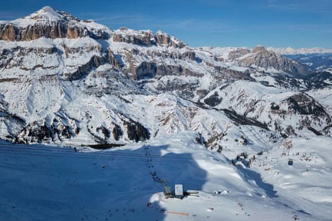 View of a ski resort piste with people skiing in Dolomites in Italy with cable car ski lift Ski area Arabba Arabba