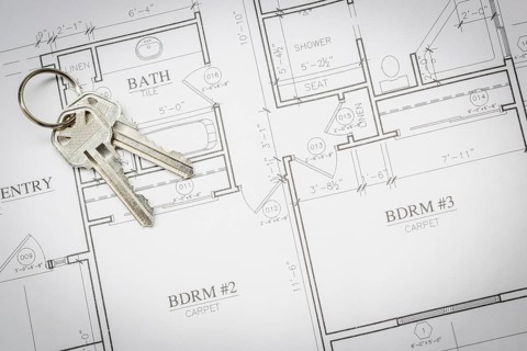 Set of new house keys resting on custom house plans