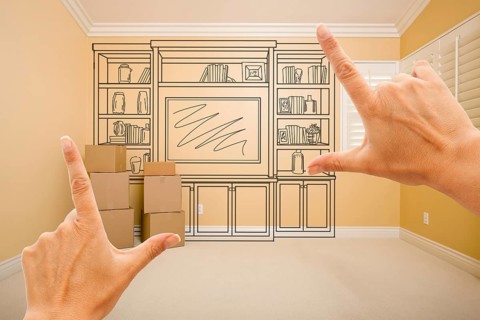 Hands framing drawing of entertainment unit in empty room with moving boxes