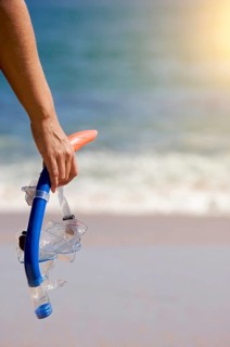 Woman holding snorkeling gear on the shoreline