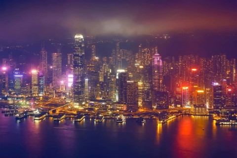 Aerial view of illuminated Hong Kong skyline cityscape downtown skyscrapers over Victoria Harbour in the evening. Hong Kong
