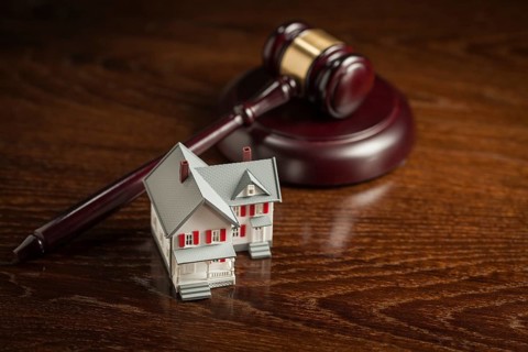 Gavel and small model house on wooden table
