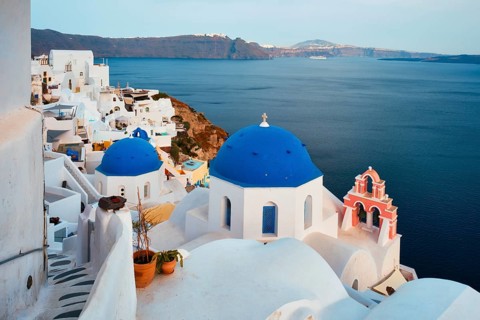 Famous view from viewpoint of Santorini Oia village with blue dome of whitewashed greek orthodox Christian church of traditional greek architecture. Oia town