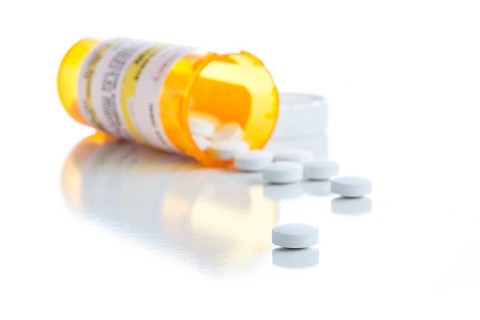Non-Proprietary medicine prescription bottle and spilled pills isolated on a white background