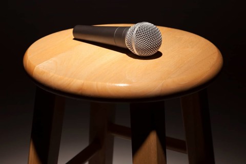 Microphone laying on wooden stool under spotlight abstract
